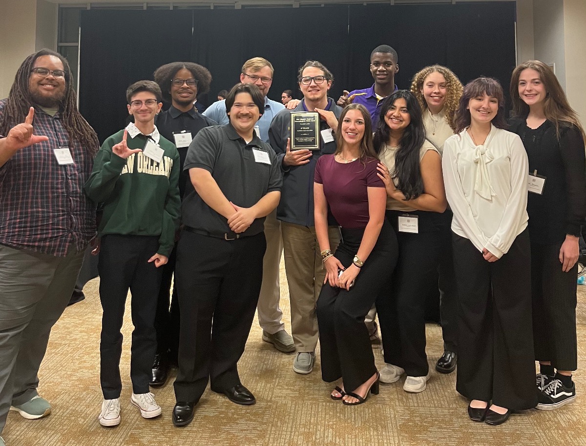 Group photo of team members showing an "L" hand signal 