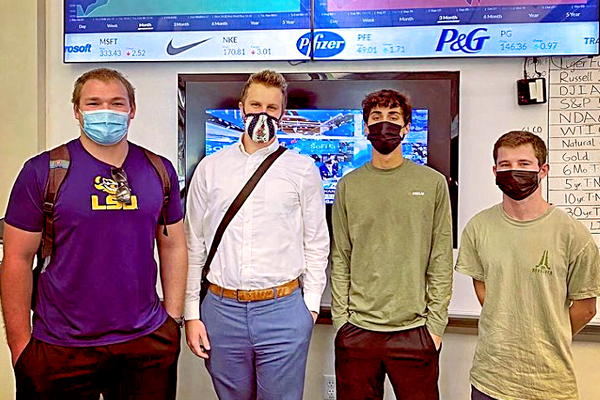 Members of the Tiger Fund team stand in front of financial data screens.