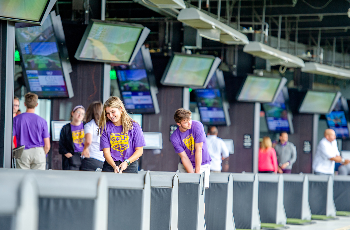 students and sponsors in the bays swinging at TopGolf