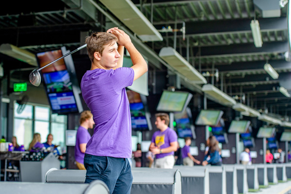 Man swing golf club at driving range.