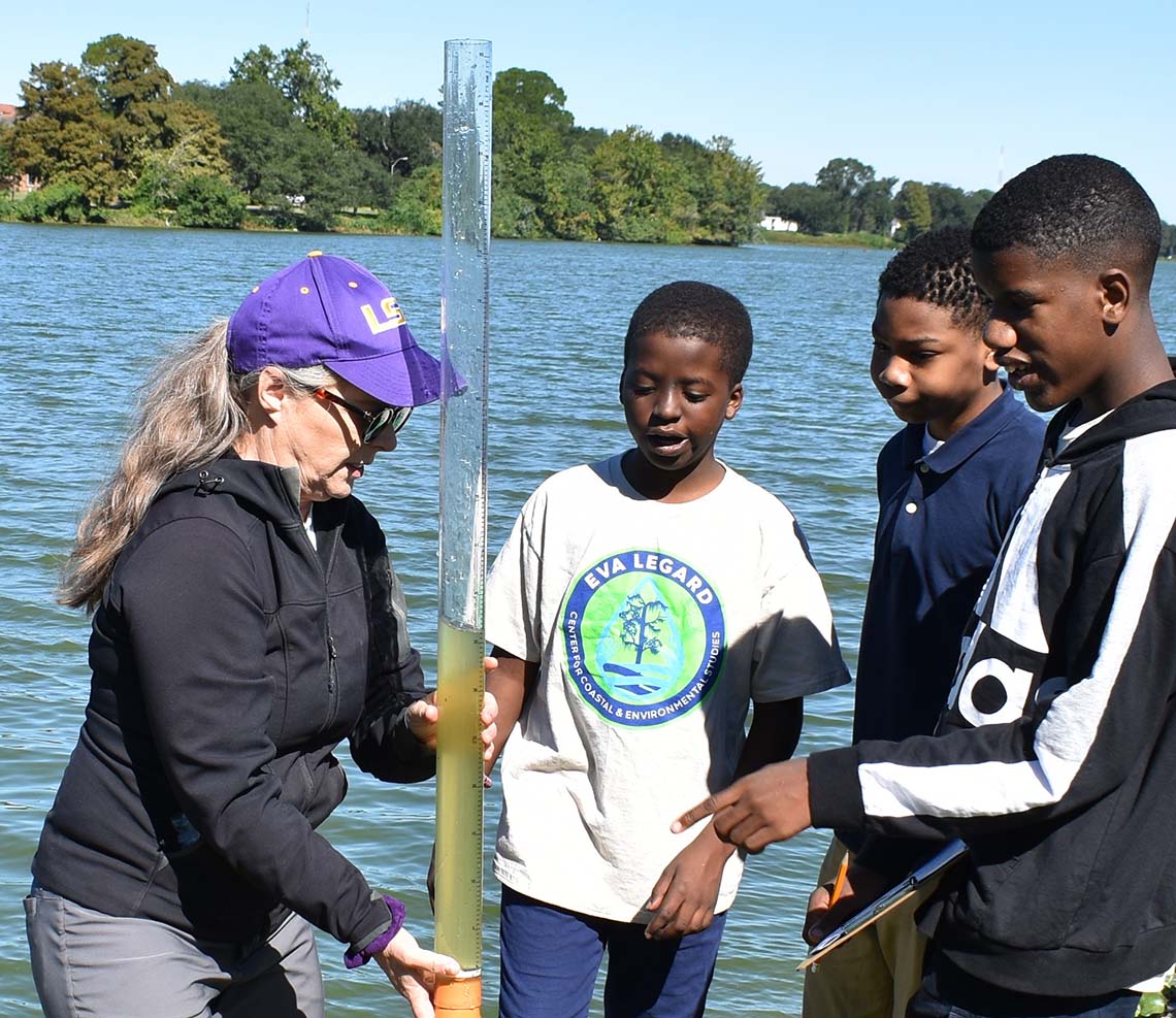 A scientist holds a tube of water in front of three middle schoolers