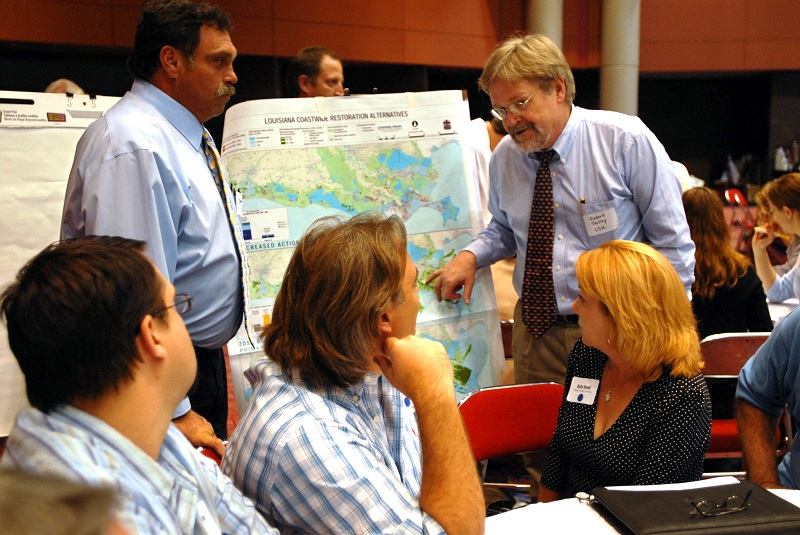 a man points to a map as a group of people watch