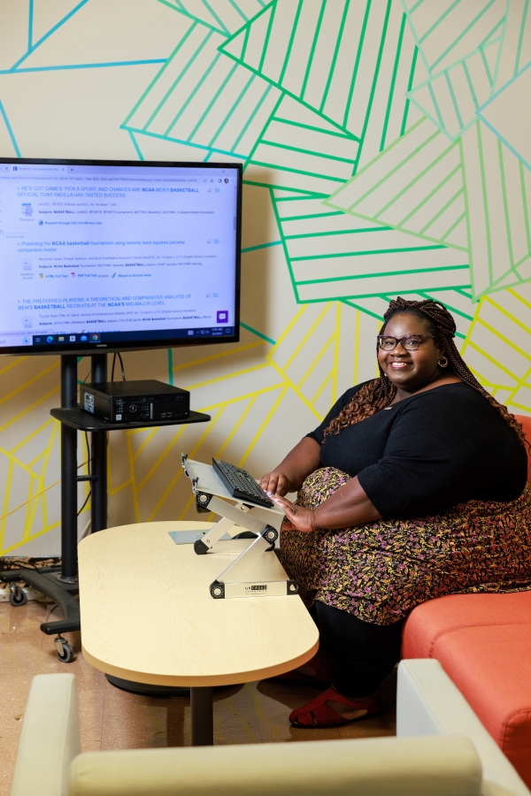 Nicollette Davis sitting on a couch infront of a computer